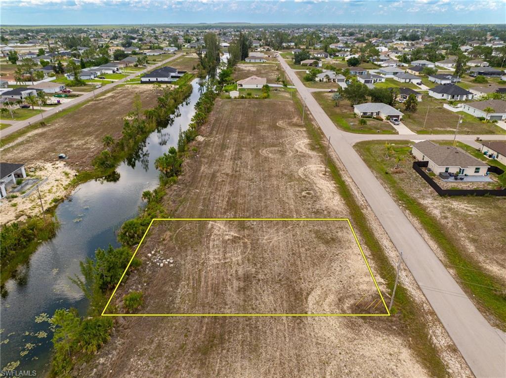 Aerial view of residential area with a large body of water and property parcel outlined