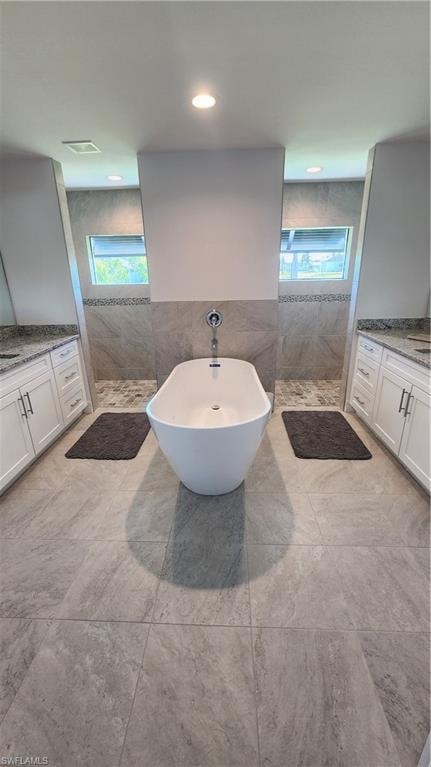 Full bath with plenty of natural light, tile walls, walk in shower, and a freestanding tub