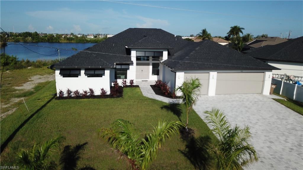 View of front facade featuring decorative driveway, an attached garage, a front yard, roof with shingles, and stucco siding