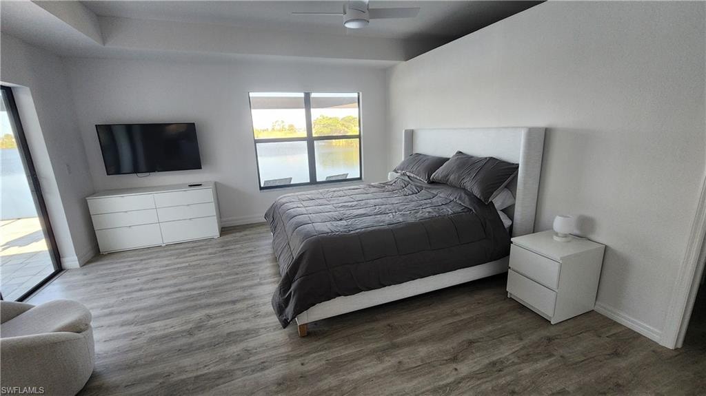 Bedroom with wood finished floors, baseboards, a ceiling fan, and access to outside