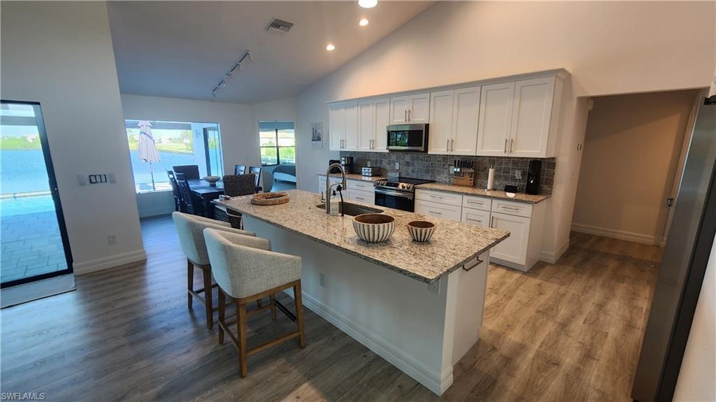 Kitchen with stainless steel appliances, a sink, baseboards, recessed lighting, and backsplash