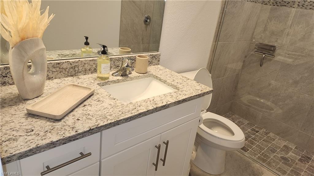 Full bathroom featuring toilet, vanity, and tiled shower
