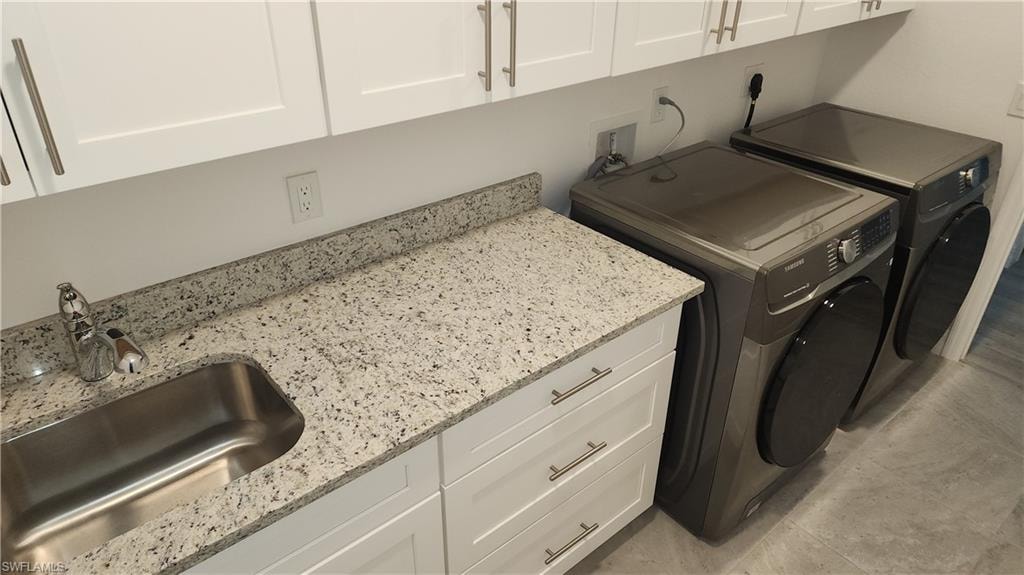 Washroom featuring cabinet space and washing machine and dryer