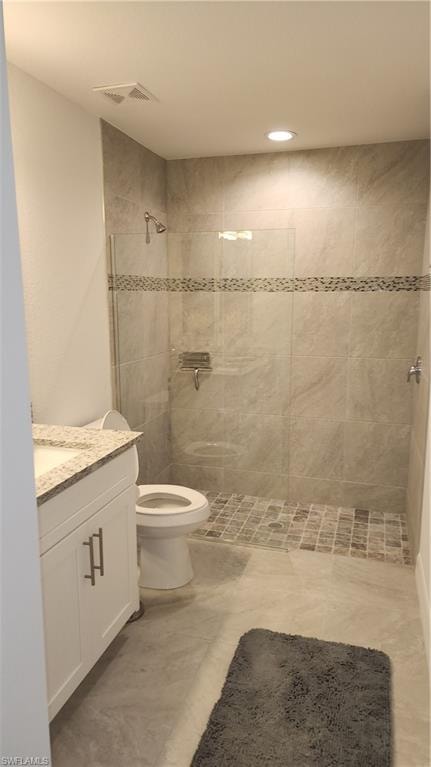 Full bath with vanity, toilet, tiled shower, and recessed lighting