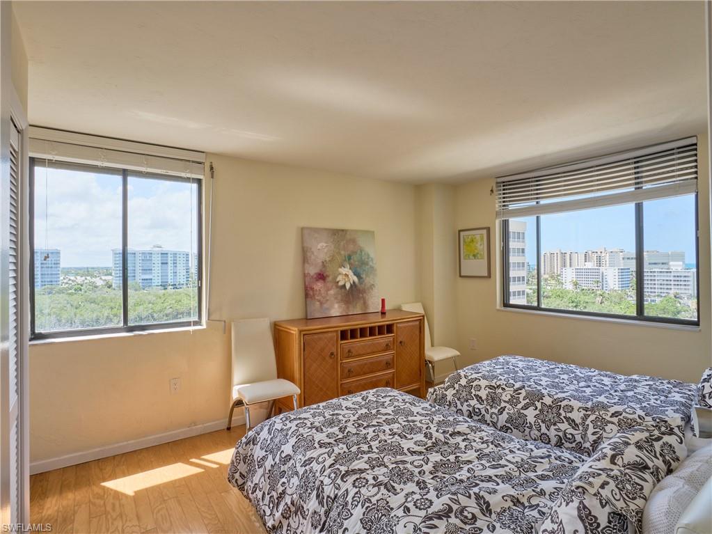 Bedroom featuring multiple windows, light wood finished floors, a view of city, and baseboards