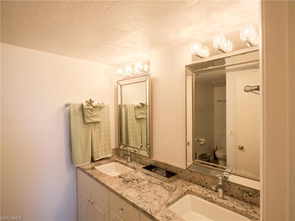 Full bathroom featuring double vanity, toilet, and a textured ceiling