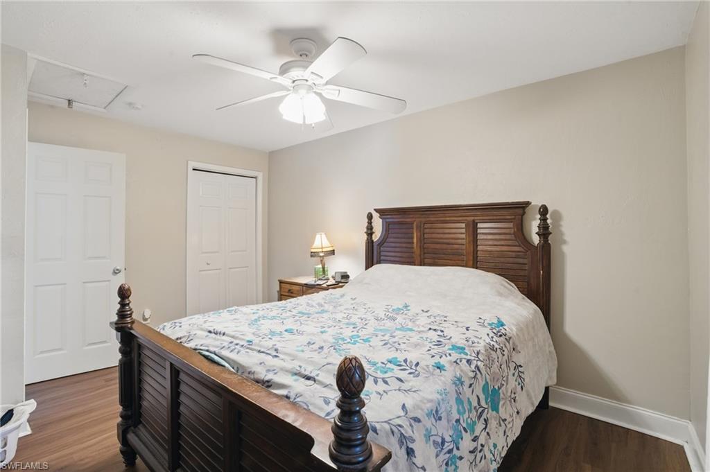 Bedroom with baseboards, wood finished floors, a closet, and attic access