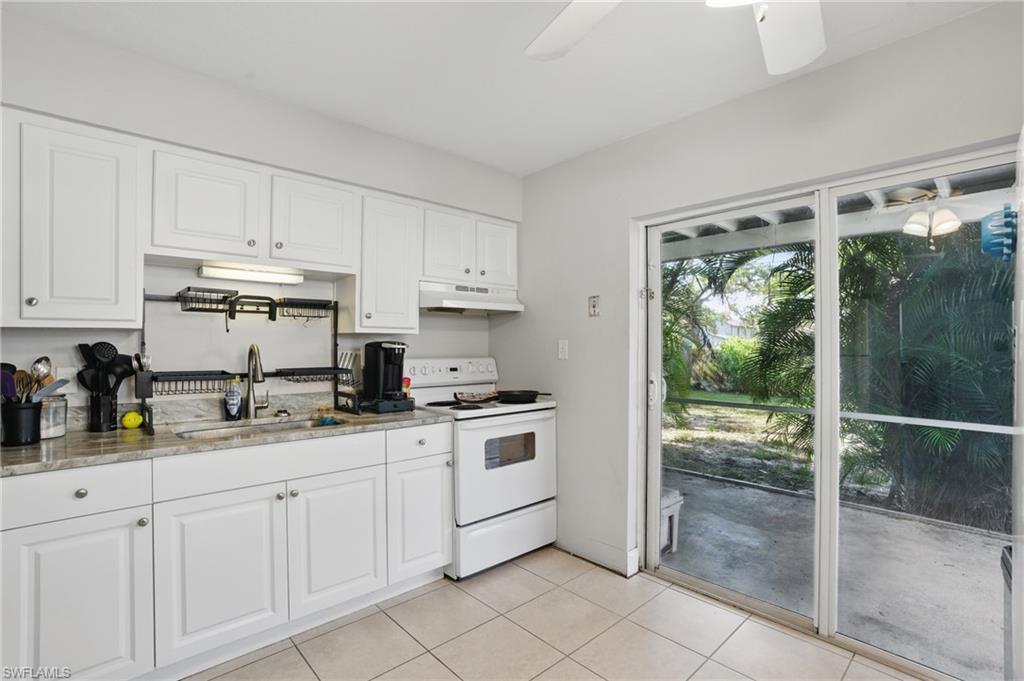 Kitchen featuring under cabinet range hood, white electric range, a sink, a ceiling fan, and white cabinetry