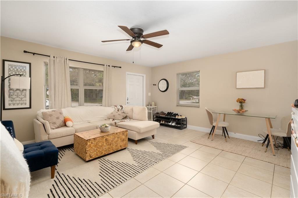 Living room with ceiling fan, light tile patterned flooring, and baseboards