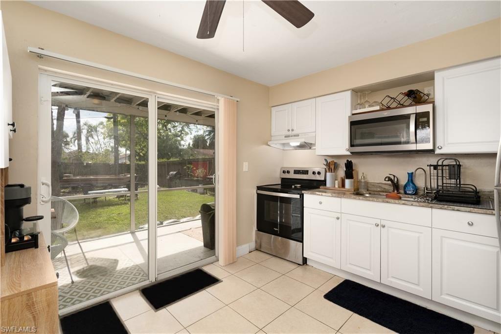 Kitchen featuring appliances with stainless steel finishes, under cabinet range hood, a sink, a ceiling fan, and white cabinets