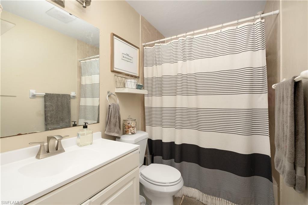 Bathroom with toilet, vanity, and a shower with curtain