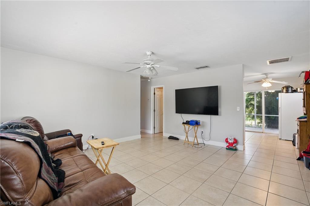 Living area with a ceiling fan, light tile patterned floors, and baseboards