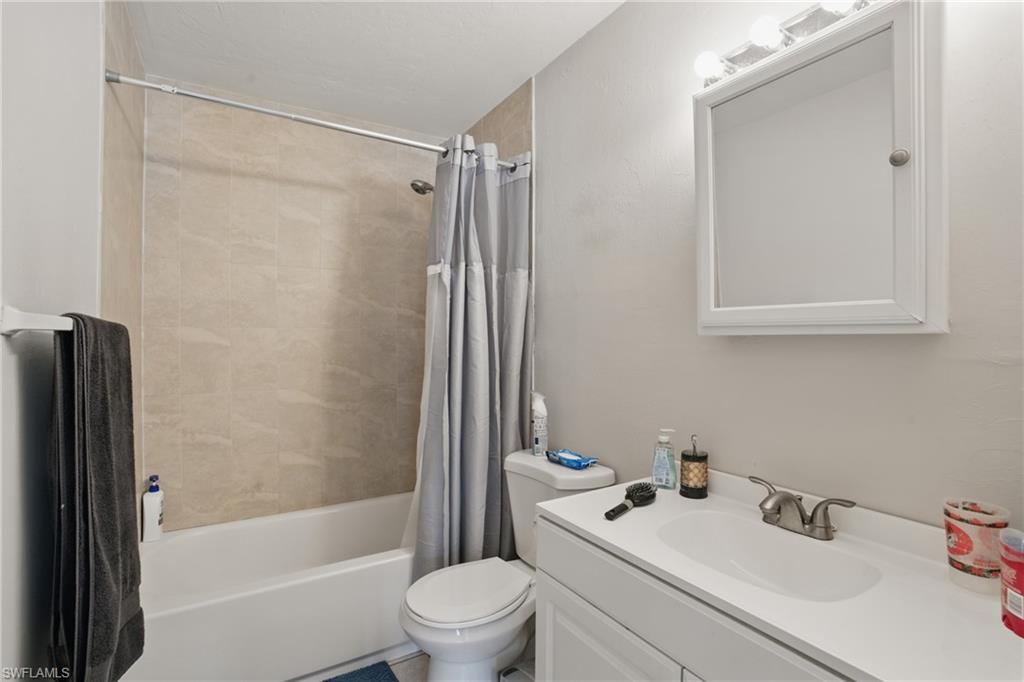 Full bathroom featuring toilet, shower / bath combination with curtain, and vanity