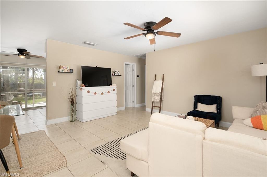 Living room with ceiling fan, light tile patterned floors, and baseboards