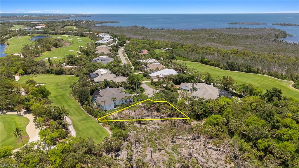 Aerial view of residential area featuring a golf club, a large body of water, and property boundaries highlighted
