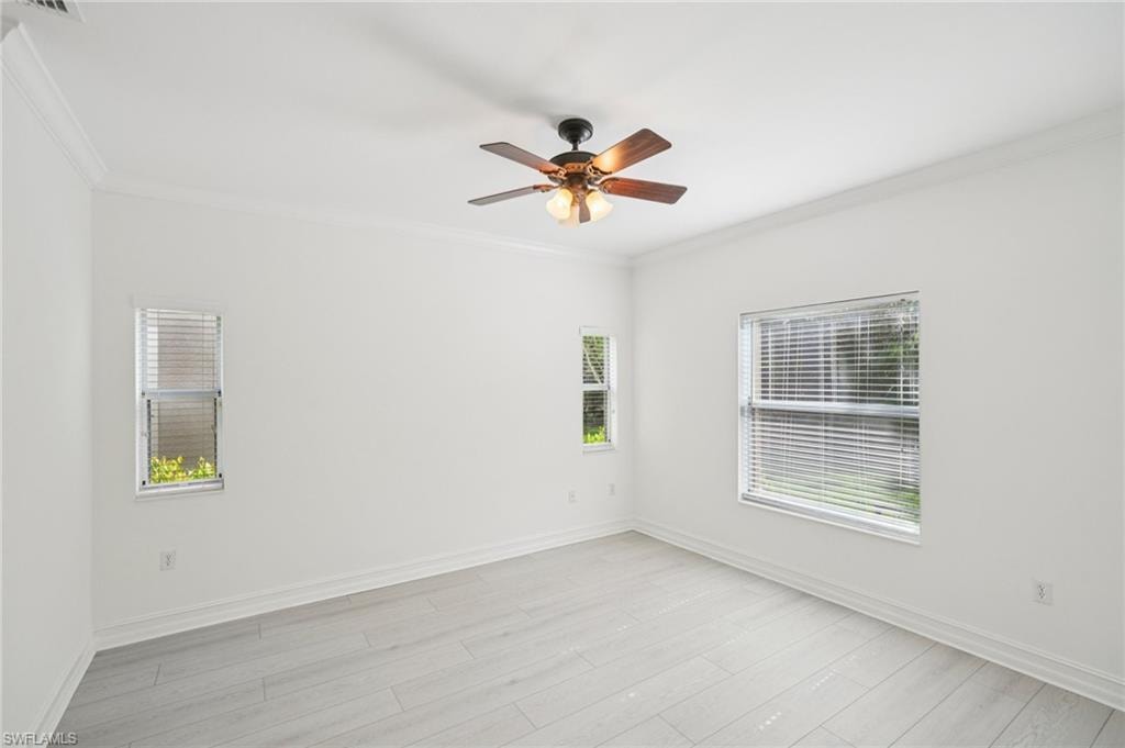Spare room with plenty of natural light, ornamental molding, ceiling fan, and light wood-style flooring
