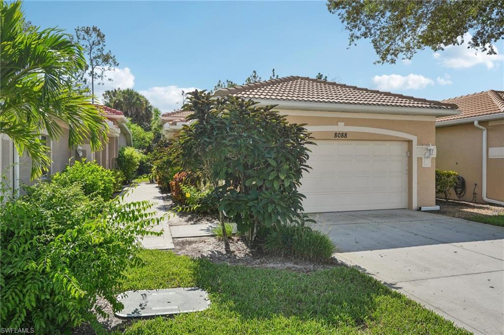View of front of house featuring a tile roof, stucco siding, driveway, and a garage