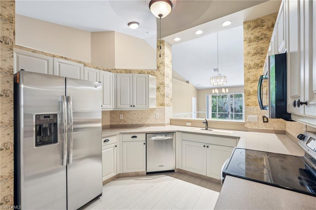Kitchen featuring stainless steel appliances, a chandelier, tasteful backsplash, light countertops, and decorative light fixtures