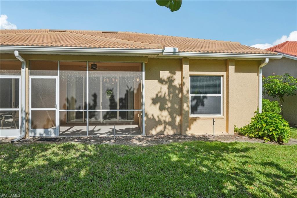 Back of property featuring a yard, stucco siding, and a sunroom