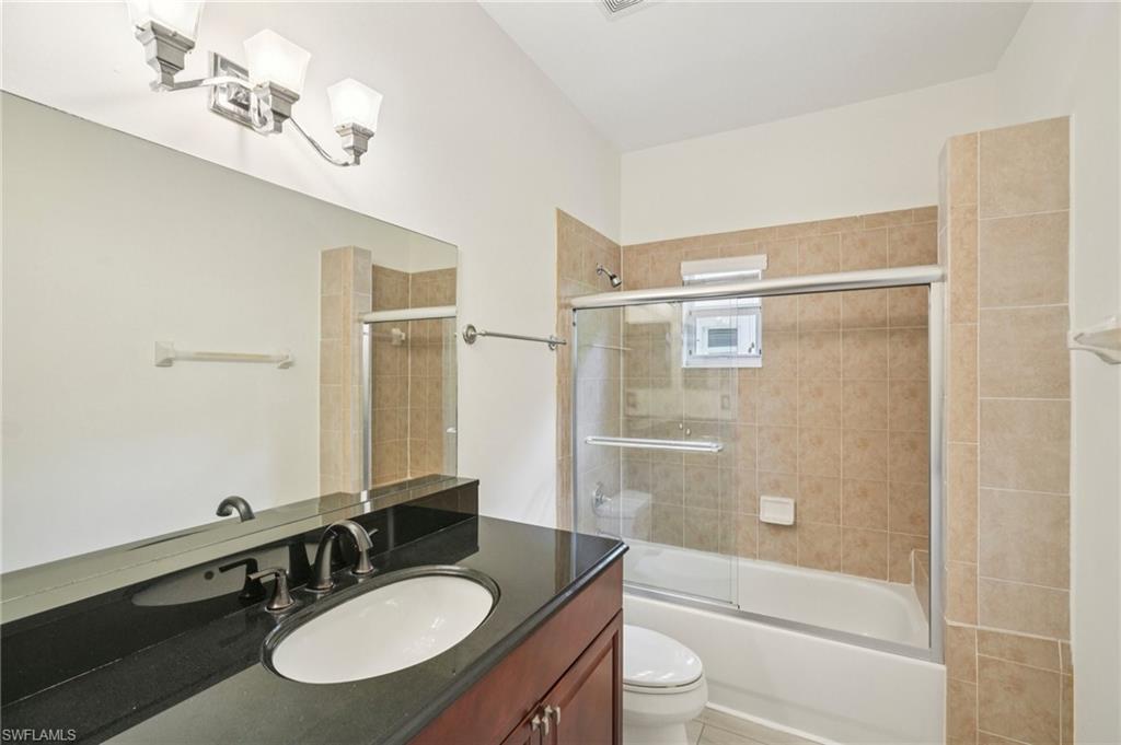 Full bath featuring vanity, enclosed tub / shower combo, and tile patterned flooring