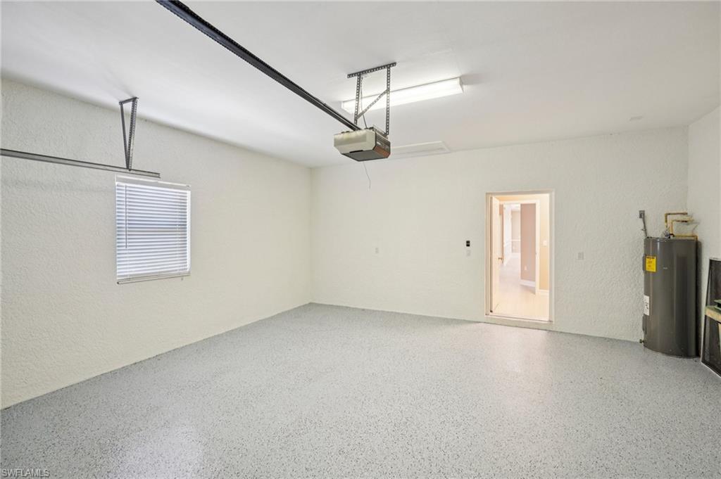 Garage featuring electric water heater, a textured wall, and a garage door opener