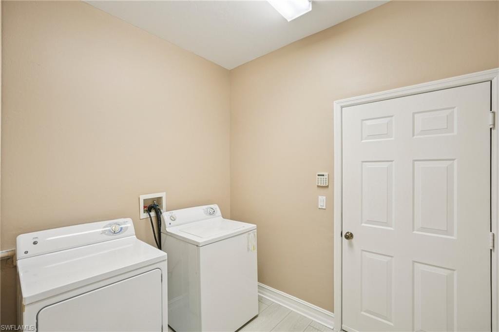 Washroom featuring washing machine and clothes dryer and baseboards
