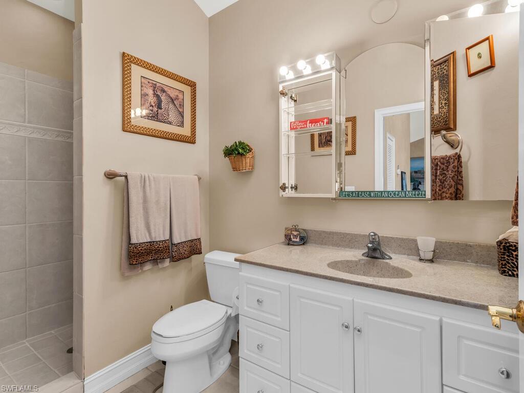Bathroom with tiled shower, vanity, and toilet