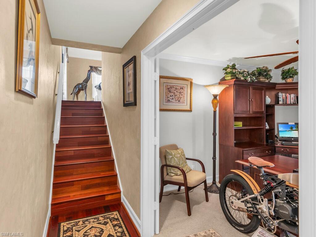 Staircase with ceiling fan, ornamental molding, and carpet floors