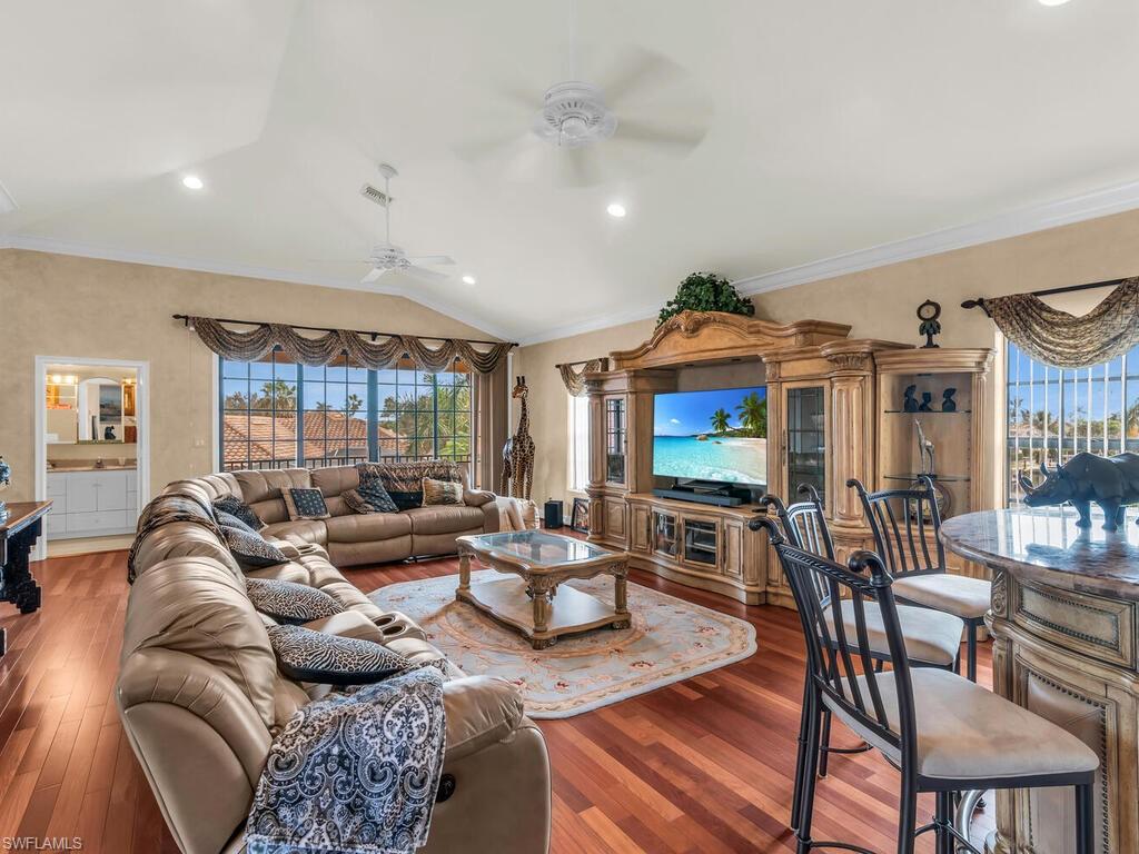 Living room featuring crown molding, wood-type flooring, and vaulted ceiling