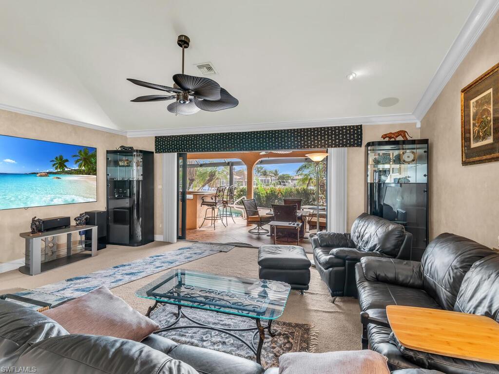 Living room with ceiling fan, crown molding, and vaulted ceiling