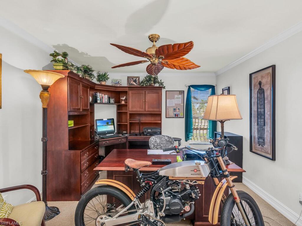 Office area featuring ceiling fan, ornamental molding, and light carpet