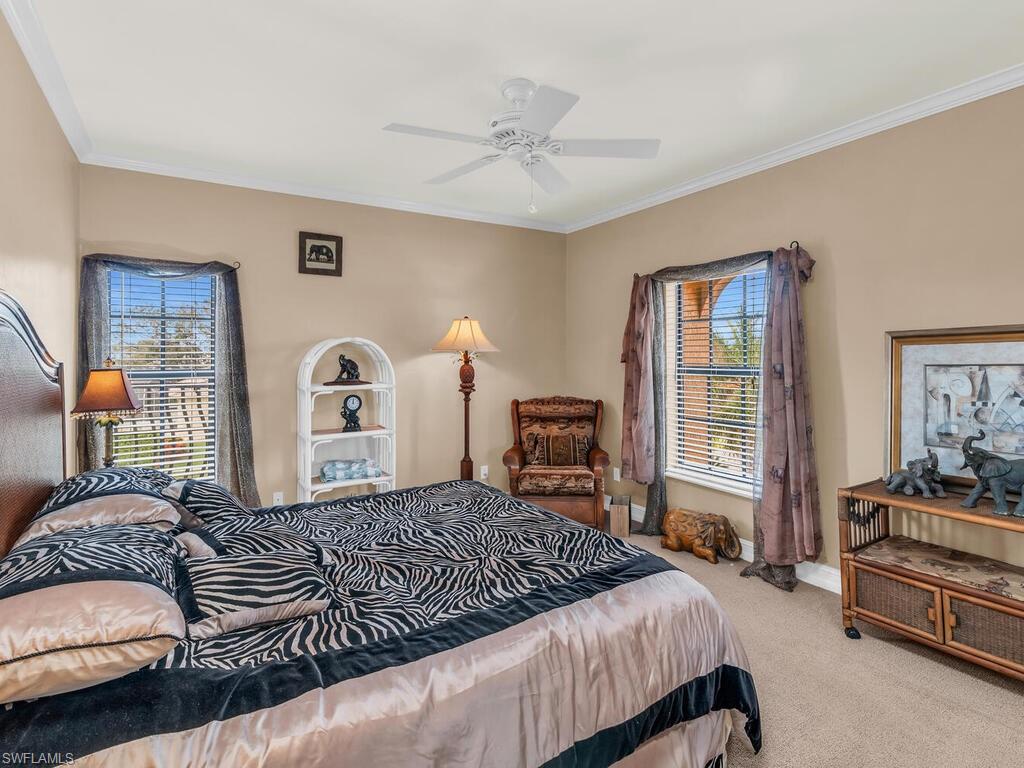 Carpeted bedroom featuring ceiling fan and ornamental molding