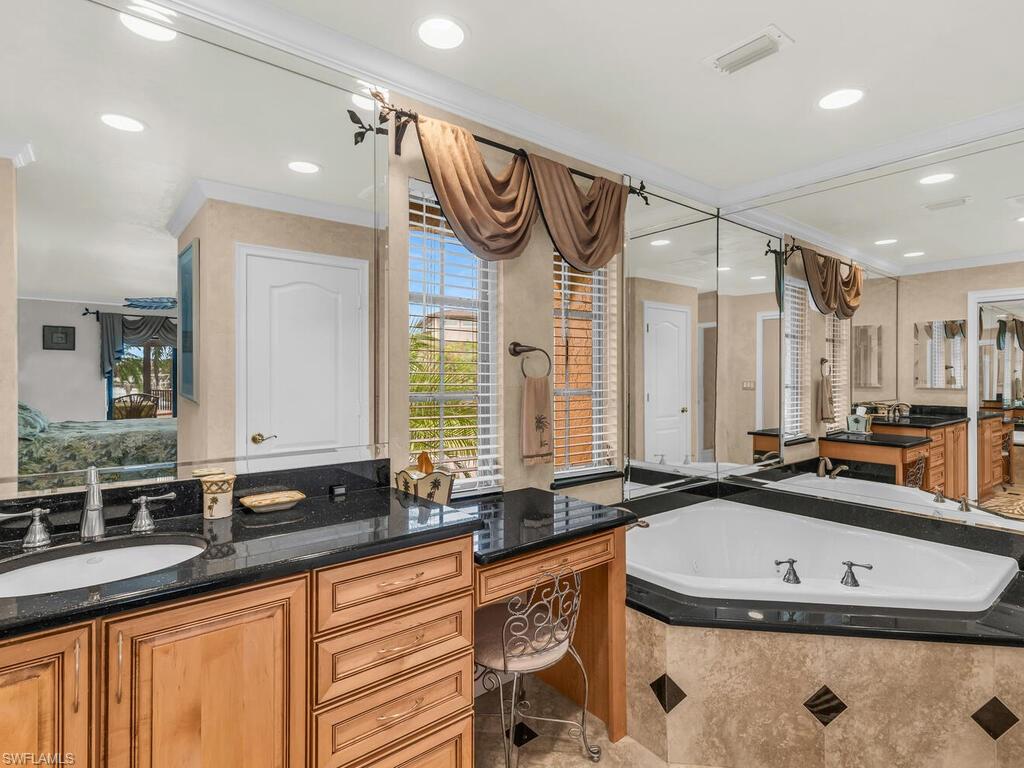 Bathroom with vanity, tiled bath, and ornamental molding