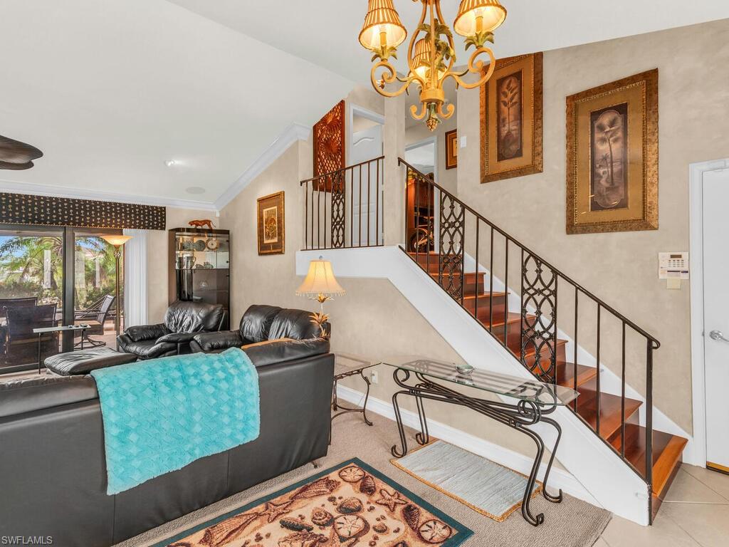 Tiled living room with an inviting chandelier, vaulted ceiling, and crown molding