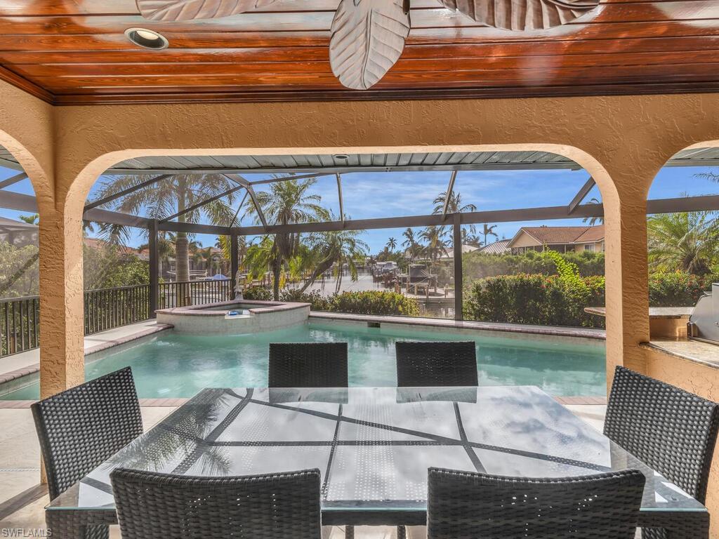 View of swimming pool featuring glass enclosure and an in ground hot tub