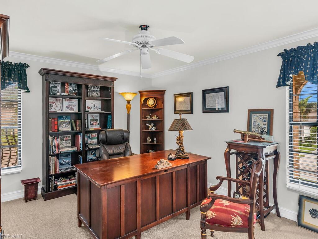 Home office featuring ceiling fan, crown molding, and light carpet