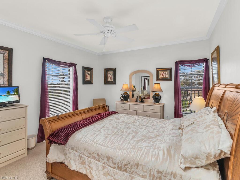 Bedroom featuring light colored carpet, multiple windows, ornamental molding, and ceiling fan