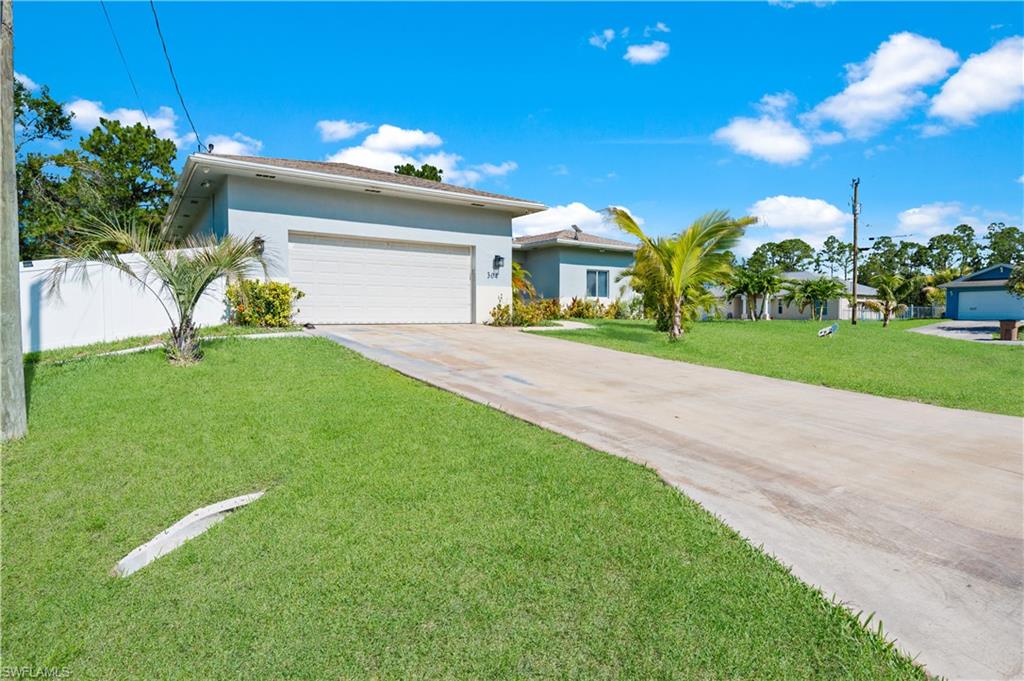 View of front of house featuring concrete driveway, stucco siding, a garage, and a front lawn