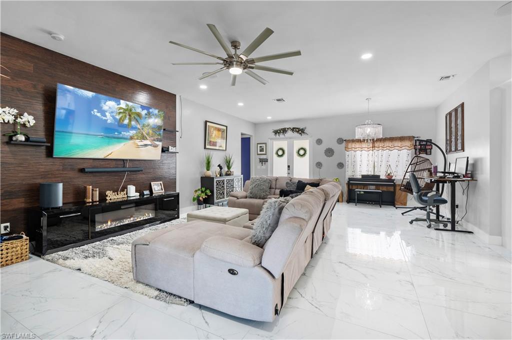 Living area featuring marble tiled flooring, a ceiling fan, recessed lighting, an accent wall, and wooden walls