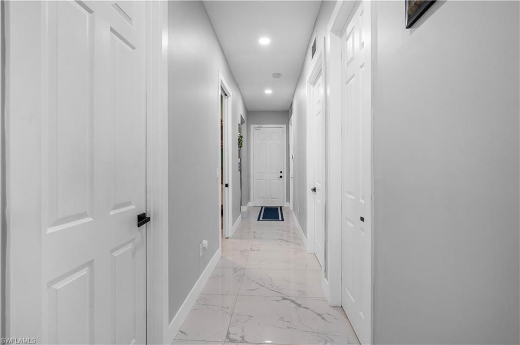 Hallway with light marble finish floors, baseboards, and recessed lighting
