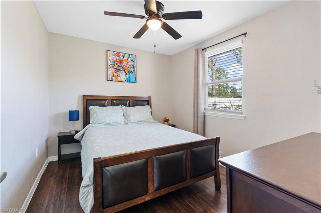 Bedroom featuring dark wood-type flooring, baseboards, and a ceiling fan