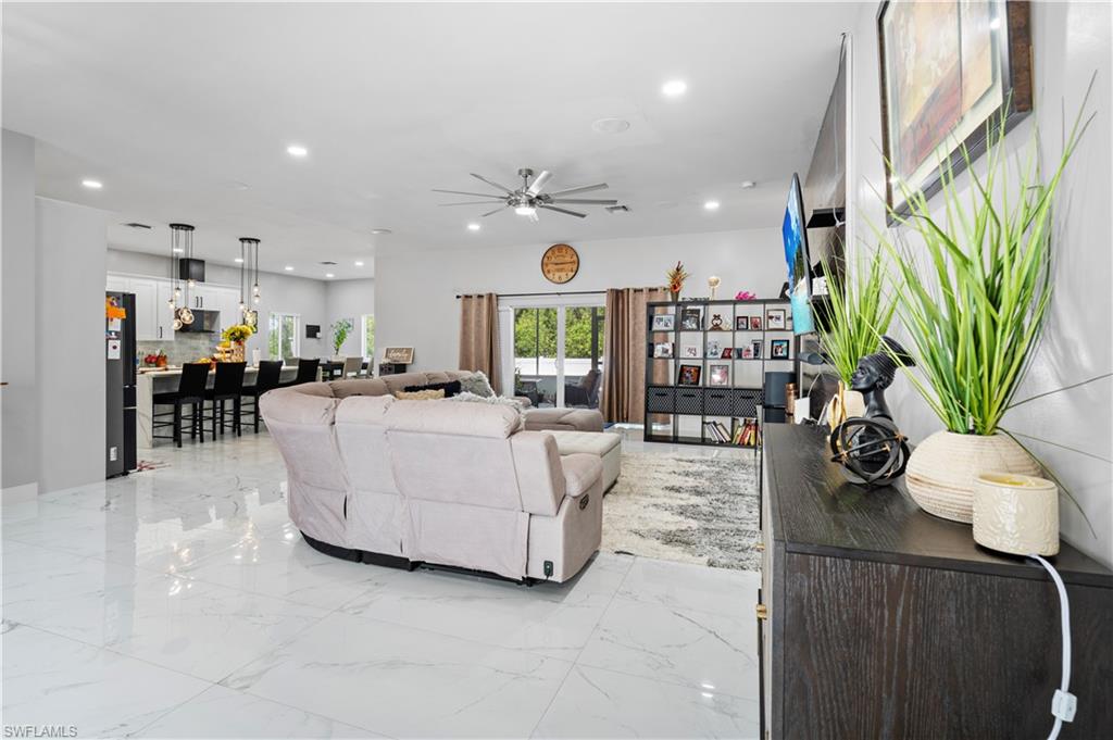 Living room featuring a ceiling fan, recessed lighting, and light marble finish flooring
