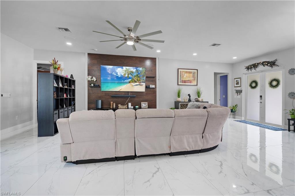 Living area with a ceiling fan, recessed lighting, light marble finish floors, and baseboards