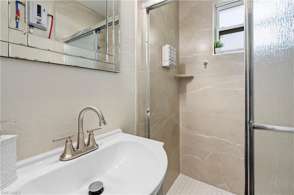 Bathroom featuring a sink, a stall shower, and a textured wall