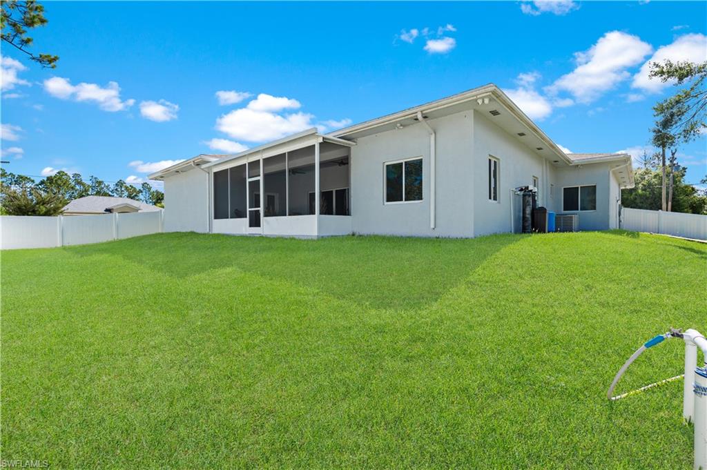 Rear view of house with a sunroom, stucco siding, and cooling unit