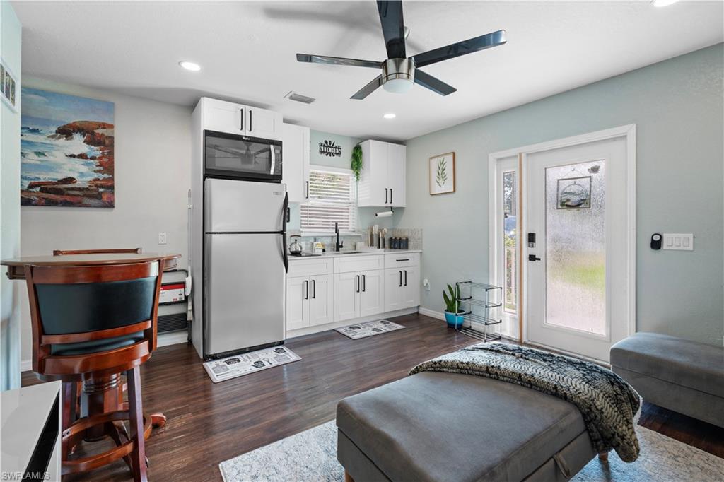 Living room with recessed lighting, dark wood-type flooring, ceiling fan, and baseboards