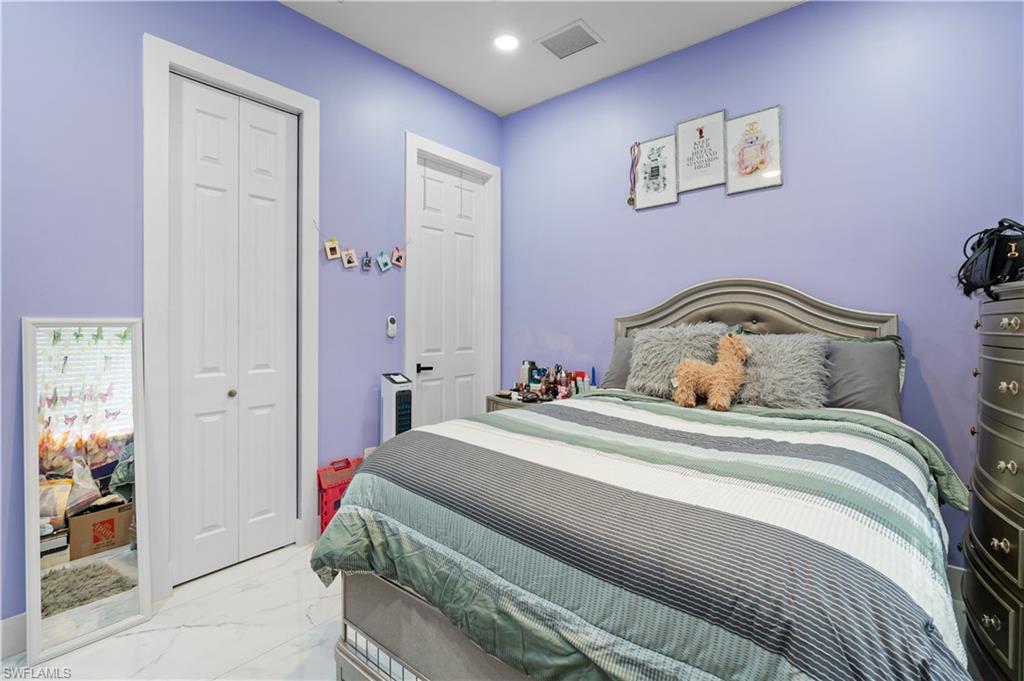 Bedroom with marble look tiles, a closet, and recessed lighting