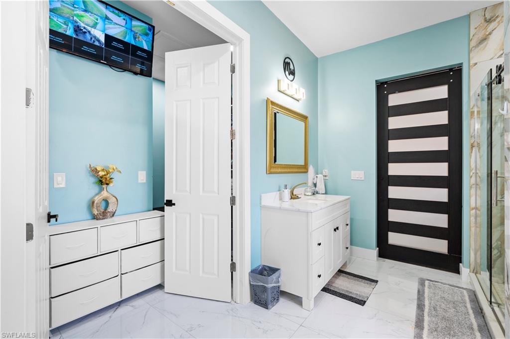 Full bath featuring marble finish floors, vanity, and a stall shower