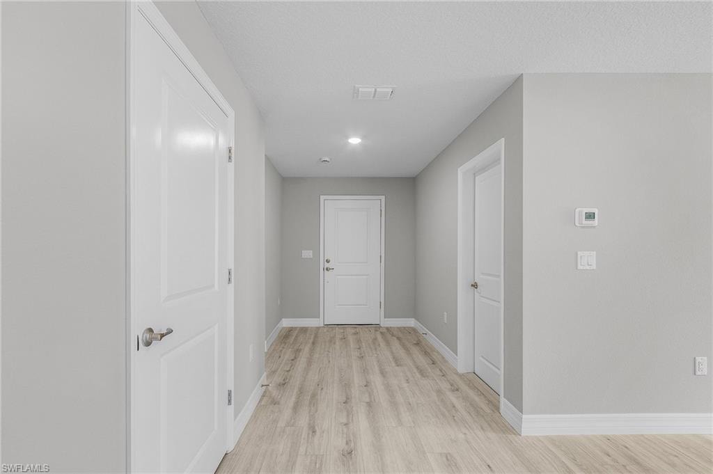 Corridor with light wood-style flooring and baseboards