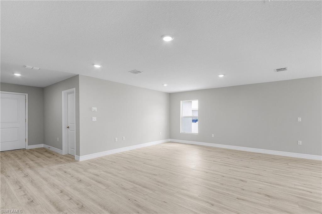 Unfurnished room featuring light wood finished floors, baseboards, recessed lighting, and a textured ceiling